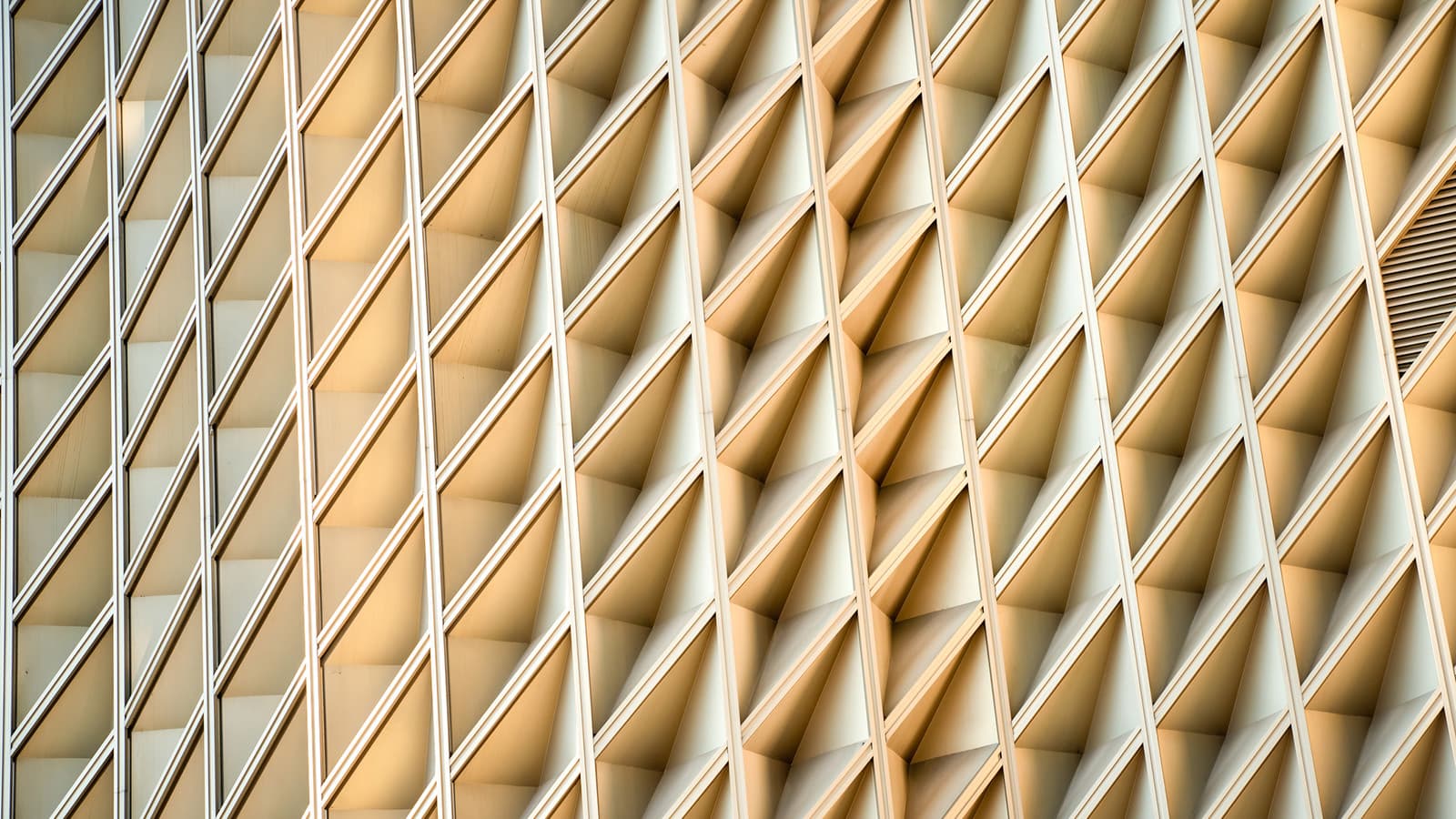 Cream-coloured building exterior with geometric detail, criss-crossing framework.